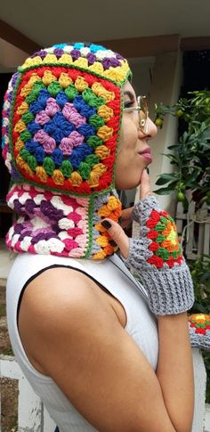 a woman wearing a multicolored crocheted granny hat and mittens on her head