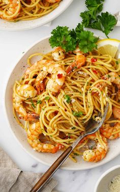 two plates of pasta with shrimp and parsley