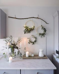 a kitchen counter topped with candles and greenery