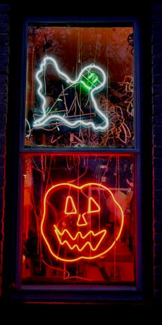 two windows decorated with neon lights and pumpkins