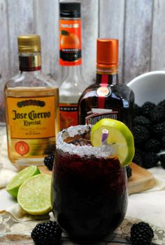 an alcoholic cocktail with blackberries and limes