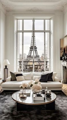 a living room with white furniture and a large window overlooking the eiffel tower