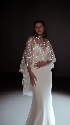 a pregnant woman in a white gown with stars on the top and cape over her head