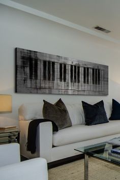 a living room filled with furniture and a painting on the wall above it's piano keyboard