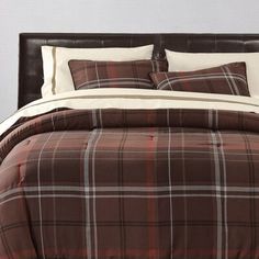 a bed with brown and white plaid comforter set on it's headboard