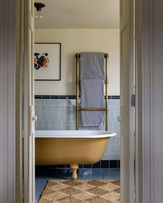 a bath tub sitting in the middle of a bathroom next to a doorway with a towel hanging on it