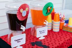 a table topped with two cups filled with liquid and paper flowers on top of it