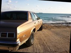 an old car is parked on the side of the road near the water and beach