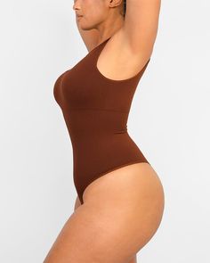 Made from recycled sculpting fabric with forward, asymmetrical cut-out detail, this bodysuit lifts and smooths. Perfect for layering under clothes or wearing alone as a super flattering all-in-one style. Why you'll love it!• Functional bodysuit with fashion.• Knitted from recycled fabric.• Built-in removable pads.• Hidden knit-in panel for 360° of tummy shaping and support.• Cool, asymmetrical cut-out detail.• Thong-cut bottom for seamless wear.• Snap closures at the bottom for easy undoing.