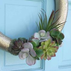 a wreath with succulents and other plants is hanging on a door handle