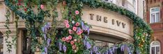 the ivy covered building has pink flowers growing on it's sides and green vines