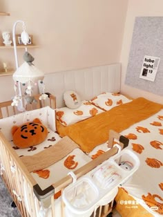 a child's bed with an orange teddy bear pillow on it and other items