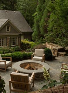 a fire pit surrounded by chairs in front of a house