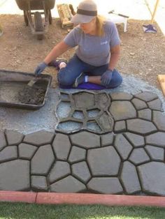 a woman sitting on the ground working with cement