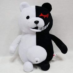 a black and white teddy bear with red eyes sitting on a white background next to a measuring tape