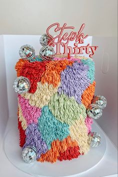 a birthday cake with colorful icing and decorations on it's side, sitting in a white box