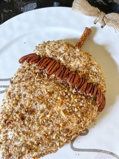 a white plate topped with a piece of cake covered in pecans and nuts on top of it