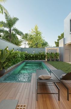 an outdoor swimming pool surrounded by greenery and wooden decking with lounge chairs around it