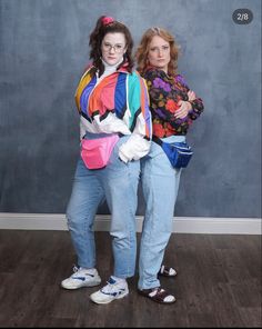 two women standing next to each other in front of a wall