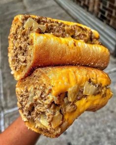 two tasty looking pastries with meat and cheese on them being held by someone's hand