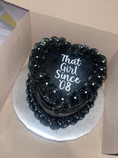 there is a black cake with white writing on it in a box that says, that girl since 08