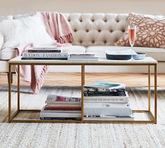 a white couch sitting next to a coffee table filled with books