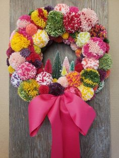 a colorful wreath hanging on the side of a wooden door decorated with pom - poms