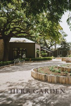 the herb garden is surrounded by stone walls and trees in front of an open building