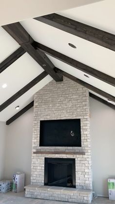 a living room with a brick fireplace and vaulted ceiling, white painted walls and exposed wood beams