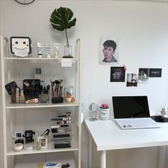 a white desk topped with a laptop computer next to a shelf filled with makeup and other items