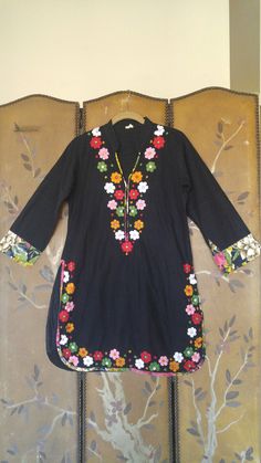 "80s Unusual black tunic Indian dress. Medium length sleeves with floral cuffs. Long splits up sides. Small stand up collar and deep V which is trimmed in floral fabric. Colourful embroidered flowers with little mirror centres around hem and sides and down the v neck sides. Made in India Size label says 40 however the bust is more a small 36 Bust 34 / 36 small Sleeves 19 inches Shoulders 14 1/2 inches Length 33 1/2 inches Waist 34\" Hips 38inches" Cotton Long Sleeve Dress With Mirror Work, Long Sleeve Cotton Dress With Mirror Work, Spring Cotton Kurta With Mirror Work, Spring Long Sleeve Kurta With Embroidered Cuffs, Spring Kurta With Embroidered Cuffs And Long Sleeves, Summer Long Sleeve Kurta With Mirror Work, V-neck Kurta With Floral Embroidery For Spring, Spring V-neck Kurta With Floral Embroidery, Floral Embroidery V-neck Kurta For Spring