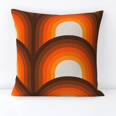 an orange and brown pillow on a white surface with the sun shining through it's arches