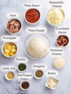 the ingredients for pizza dough laid out on a white marble counter top, including parmesan cheese, pineapple, parmesan sauce, and pepper