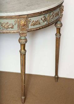 an ornately decorated console table with marble top and gold trimmings on the legs