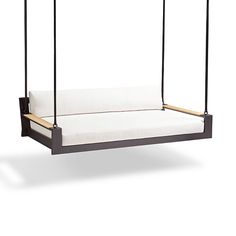 a black swing bed with white pillows on it's sides and two wooden posts