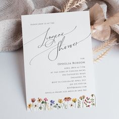 an elegant floral bridal shower is displayed on a white tablecloth with feathers and flowers