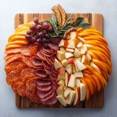 a wooden cutting board topped with sliced fruits and meats on top of each other