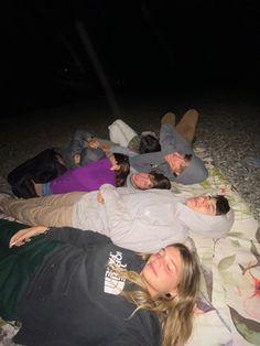 four people laying on the ground at night with their eyes closed and one person taking a selfie