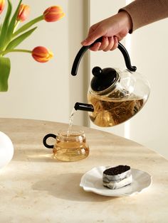 a person pouring tea into a cup on a table