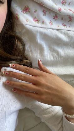 a woman laying on top of a bed holding onto her hand