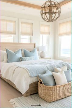 a bed with blue and white pillows in a bedroom next to a chandelier