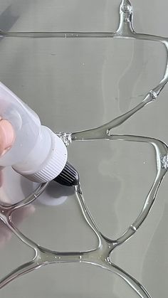 a person is using a bottle to clean the surface of a metal table that has been painted silver