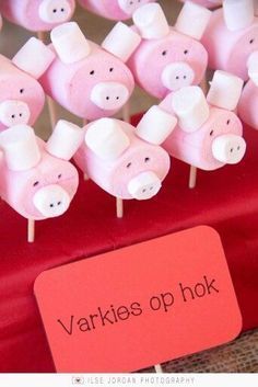 there are many small pink pigs on the sticks with name tags in front of them