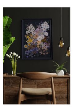 a painting hanging on the wall next to a wooden table with flowers in vases