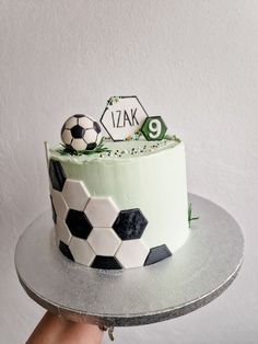 a hand holding a cake with soccer themed frosting on it, and the number 9