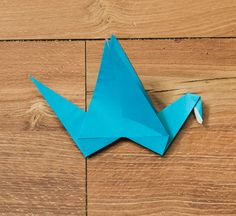 an origami bird sitting on top of a wooden floor