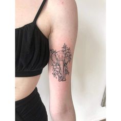 an elephant and flowers tattoo on the left upper half of the arm is shown in black ink