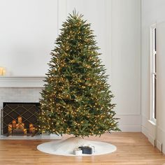 a small christmas tree in a living room next to a fire place with candles on it