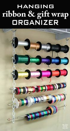 the hanging ribbon and gift wrap organizer is organized with spools of colored thread