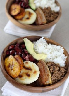 two wooden bowls filled with different types of food on top of white cloth napkins